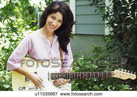 Stock Photo - Portrait of a mature woman playing the guitar. Fotosearch