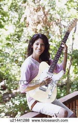 Stock Photo - Portrait of a mature woman playing the guitar. Fotosearch