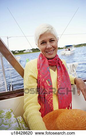 Stock Image - Portrait of a mature woman sitting in a boat and smiling. Fotosearch