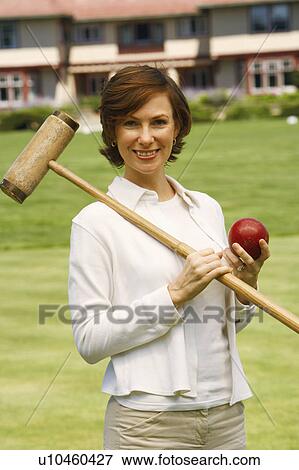 Stock Photo - Portrait of a mid adult woman holding a croquet mallet and a ball. Fotosearch