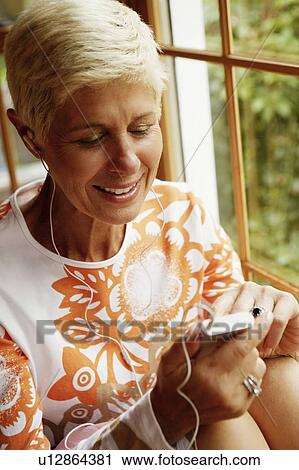Stock Image - Senior woman listening to music and smiling. Fotosearch