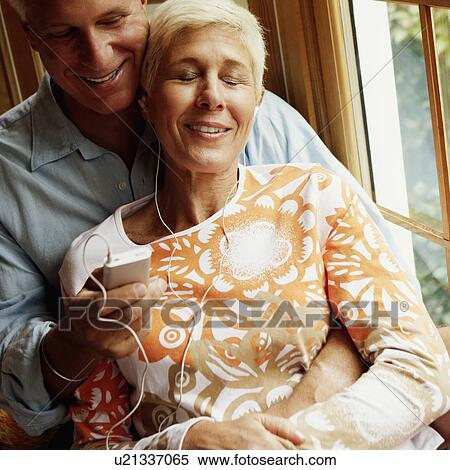 Stock Photography - Senior woman listening to music with a mature man holding an Ipod. Fotosearch