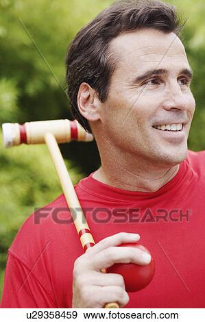 Close-up of a mature man holding a croquet mallet and a ball View Large Photo Image Stock Photo - Close-up of a mature man holding a croquet mallet and a ball. Fotosearch