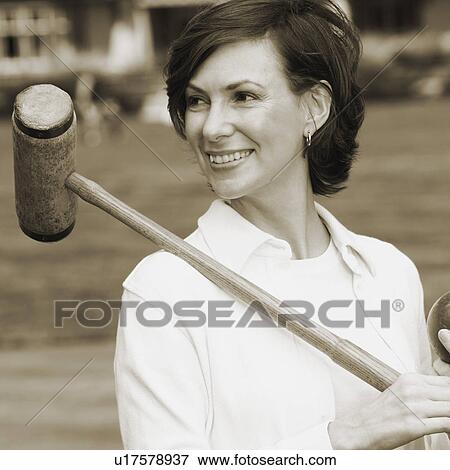 Stock Photo - Close-up of a mid adult woman holding a croquet mallet and a ball. Fotosearch