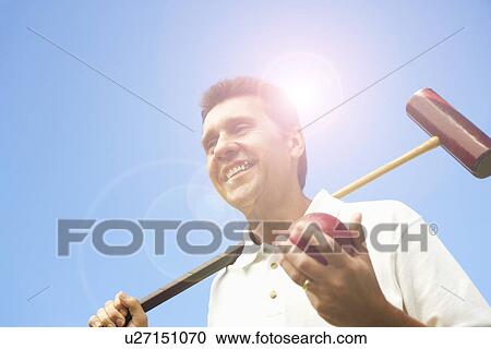 Low angle view of a mature man holding a croquet mallet and a ball View Large Photo Image Stock Image - Low angle view of a mature man holding a croquet mallet and a ball. Fotosearch