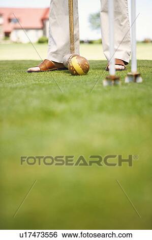 Stock Photograph - Low section view of a person playing croquet. Fotosearch