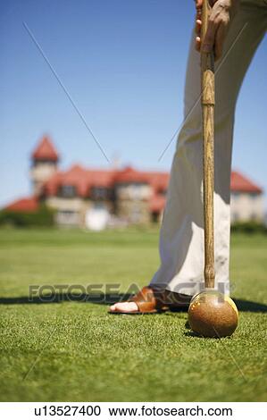 Stock Image - Low section view of a woman playing croquet in a field. Fotosearch
