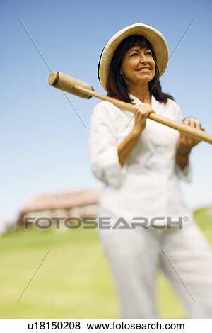 Stock Photo - Mature woman holding a croquet mallet and a ball. Fotosearch