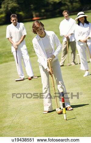 Mid adult woman playing croquet with a mature couple and a mid adult man standing behind her View Large Photo Image Stock Image - Mid adult woman playing croquet with a mature couple and a mid adult man standing behind her. Fotosearch