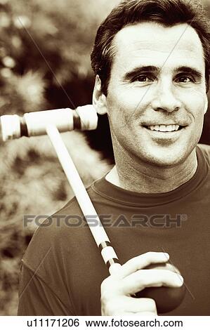 Stock Photograph - Portrait of a mature man holding a croquet mallet and a ball. Fotosearch