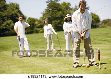 Portrait of a mid adult man playing croquet with a mature couple and mid adult woman standing behind him View Large Photo Image Stock Image - Portrait of a mid adult man playing croquet with a mature couple and mid adult woman standing behind him. Fotosearch