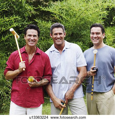 Picture - Portrait of a mid adult man with two mature men holding croquet mallets and balls. Fotosearch