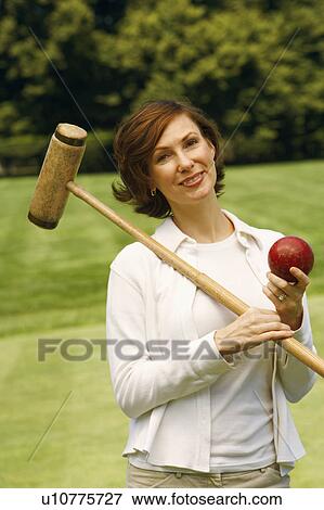 Stock Photo - Portrait of a mid adult woman holding a croquet mallet and a ball. Fotosearch
