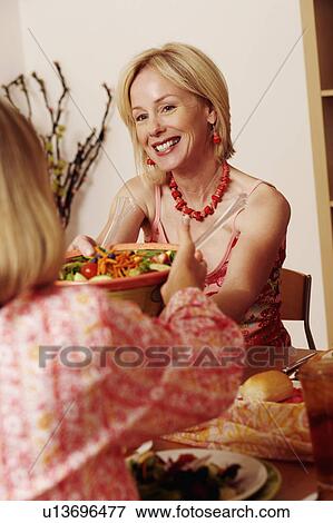 Mature woman giving a bowl of salad to her friend and smiling View Large Photo Image Stock Photo - Mature woman giving a bowl of salad to her friend and smiling. Fotosearch