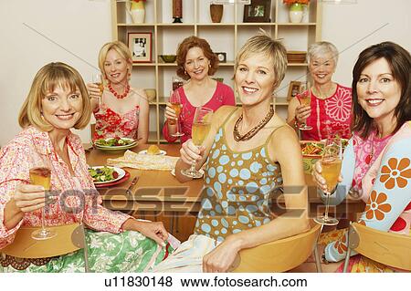 Portrait of a group of mature women sitting at the dining table and holding champagne flutes View Large Photo Image Stock Photo - Portrait of a group of mature women sitting at the dining table and holding champagne flutes. Fotosearch