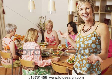 Portrait of a mature woman gesturing and her friends sitting at the dining table in the background View Large Photo Image Stock Photograph - Portrait of a mature woman gesturing and her friends sitting at the dining table in the background. Fotosearch