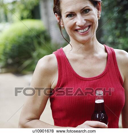 Portrait of a mature woman holding a bottle of wine and smiling View Large Photo Image Stock Photo - Portrait of a mature woman holding a bottle of wine and smiling. Fotosearch
