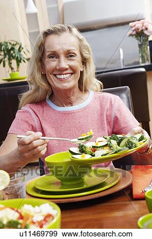 Portrait of a mature woman holding a plate of salad View Large Photo Image Stock Photo - Portrait of a mature woman holding a plate of salad. Fotosearch