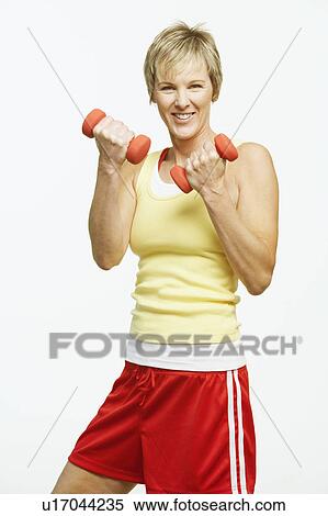 Stock Photography - Portrait of a mature woman holding dumbbells. Fotosearch