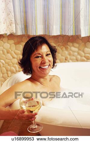 Portrait of a mature woman sitting in a bathtub and holding a glass of wine View Large Photo Image Stock Image - Portrait of a mature woman sitting in a bathtub and holding a glass of wine. Fotosearch