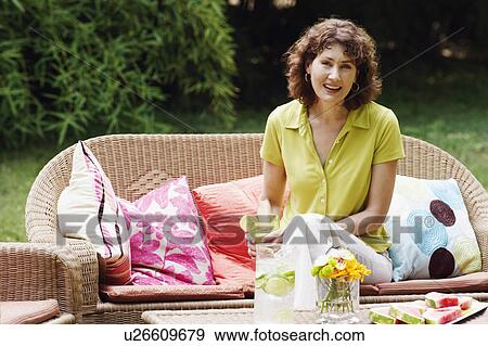 Portrait of a mature woman sitting on a couch and holding a glass of lemonade View Large Photo Image Stock Photo - Portrait of a mature woman sitting on a couch and holding a glass of lemonade. Fotosearch