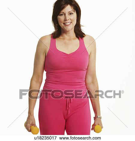 Stock Photo - Portrait of a mature woman standing and holding dumbbells. Fotosearch