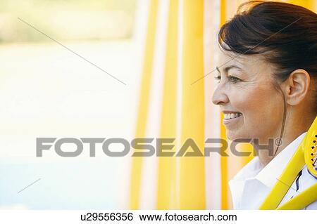 Stock Photograph - Side profile of a mature woman holding a tennis racket and smiling. Fotosearch