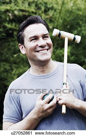 Stock Image - Close-up of a mature man holding a croquet mallet and a ball. Fotosearch