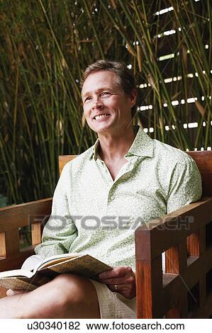 Stock Image - Close-up of a mature man sitting in an armchair and smiling. Fotosearch