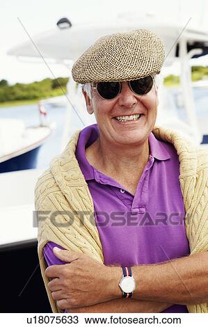 Stock Image - Close-up of a mature man smiling with his arms folded. Fotosearch