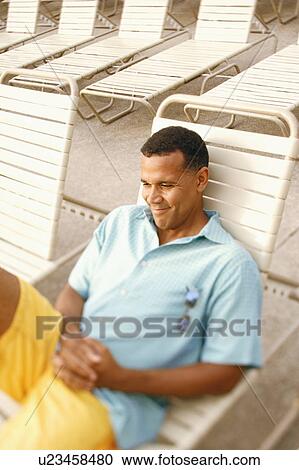 Stock Image - High angle view of a mature man reclining on a lounge chair. Fotosearch