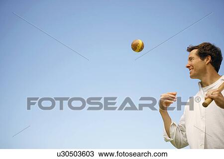 Low angle view of a mid adult man tossing a ball View Large Photo Image Stock Image - Low angle view of a mid adult man tossing a ball. Fotosearch