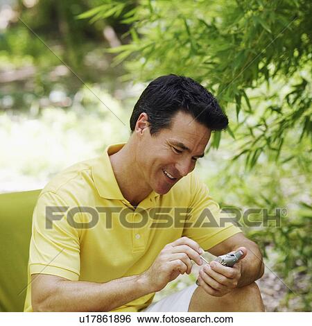Stock Photograph - Mature man operating a personal data assistant. Fotosearch