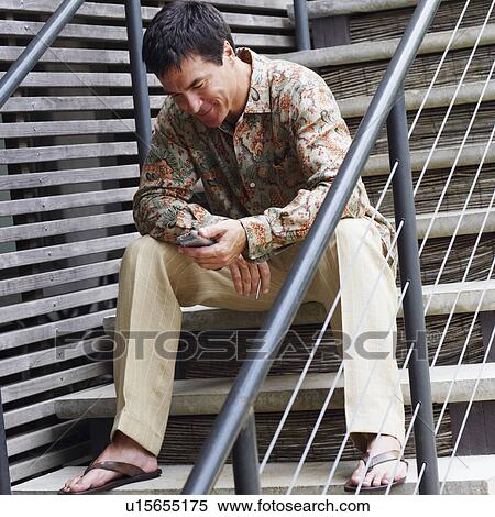 Mature man sitting on a staircase and holding a personal data assistant View Large Photo Image Stock Photography - Mature man sitting on a staircase and holding a personal data assistant. Fotosearch