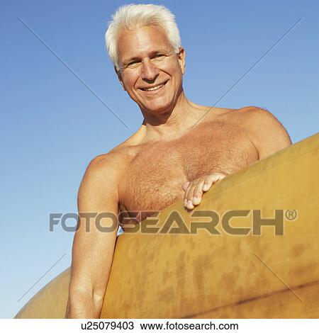 Portrait of a mature man holding a surfboard under his arm View Large Photo Image Stock Image - Portrait of a mature man holding a surfboard under his arm. Fotosearch