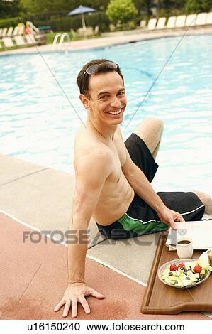 Stock Image - Portrait of a mature man sitting at the poolside. Fotosearch