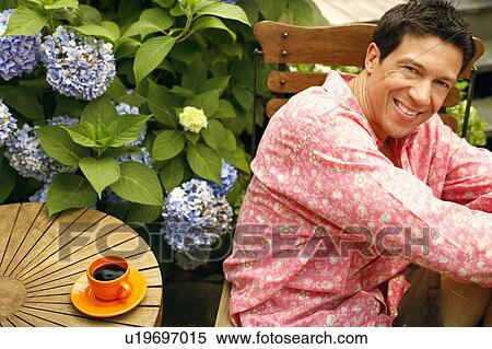Stock Photography - Portrait of a mature man sitting on a chair and smiling. Fotosearch