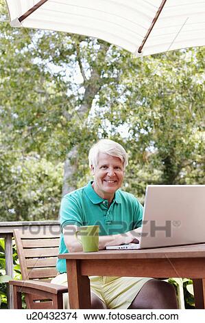Portrait of a mature man using a laptop and smiling View Large Photo Image Picture - Portrait of a mature man using a laptop and smiling. Fotosearch