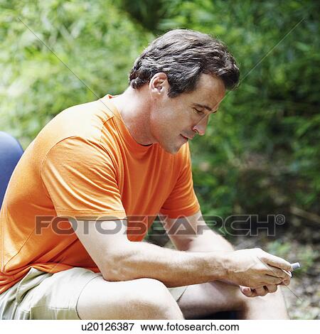 Stock Photo - Side profile of a mature man holding a personal data assistant. Fotosearch