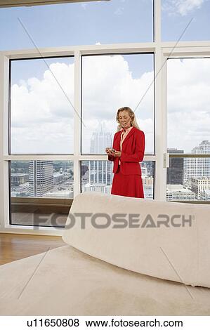 Businesswoman standing behind a couch and using a personal data assistant View Large Photo Image Stock Photo - Businesswoman standing behind a couch and using a personal data assistant. Fotosearch
