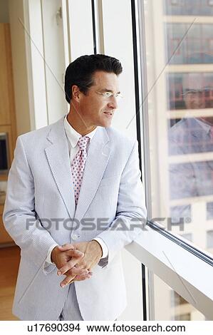 Close-up of a businessman looking through a window View Large Photo Image Picture - Close-up of a businessman looking through a window. Fotosearch