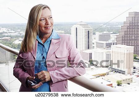 Close-up of a businesswoman holding a personal data assistant with a city in the background View Large Photo Image Stock Photo - Close-up of a businesswoman holding a personal data assistant with a city in the background. Fotosearch