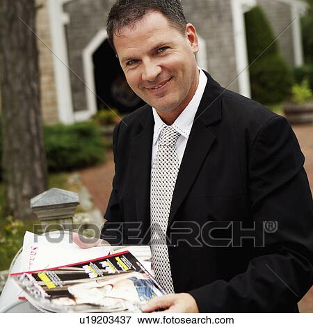 Stock Photo - Portrait of a businessman holding magazines and smiling. Fotosearch