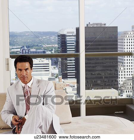 Stock Image - Portrait of a businessman sitting on a couch in an office. Fotosearch