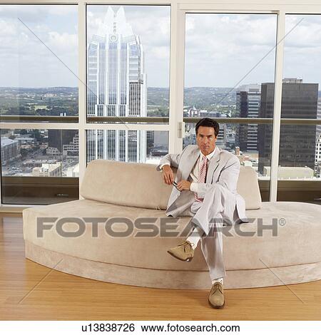 Stock Photograph - Portrait of a businessman sitting on a couch in an office. Fotosearch