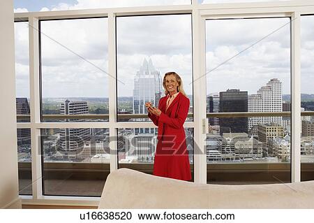 Stock Image - Portrait of a businesswoman standing behind a couch and smiling. Fotosearch