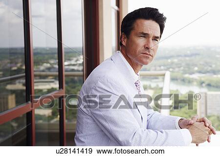 Stock Photo - Side profile of a businessman leaning against a railing. Fotosearch