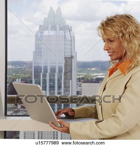 Stock Photo - Side profile of a businesswoman using a laptop. Fotosearch