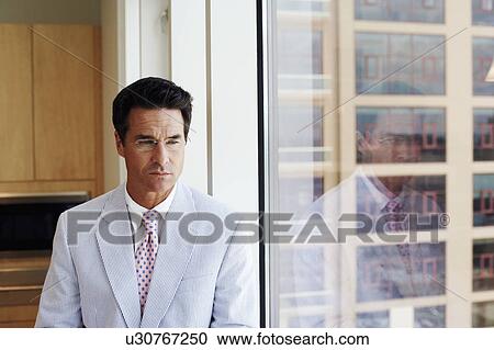 Close-up of a businessman looking through a window View Large Photo Image Stock Image - Close-up of a businessman looking through a window. Fotosearch
