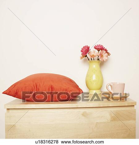 Stock Photo - Close-up of a flower vase and a cushion with a cup on the table. Fotosearch